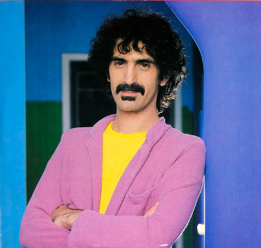 Large full-page photo of Frank Zappa wearing a pink jacket and yellow sweater 