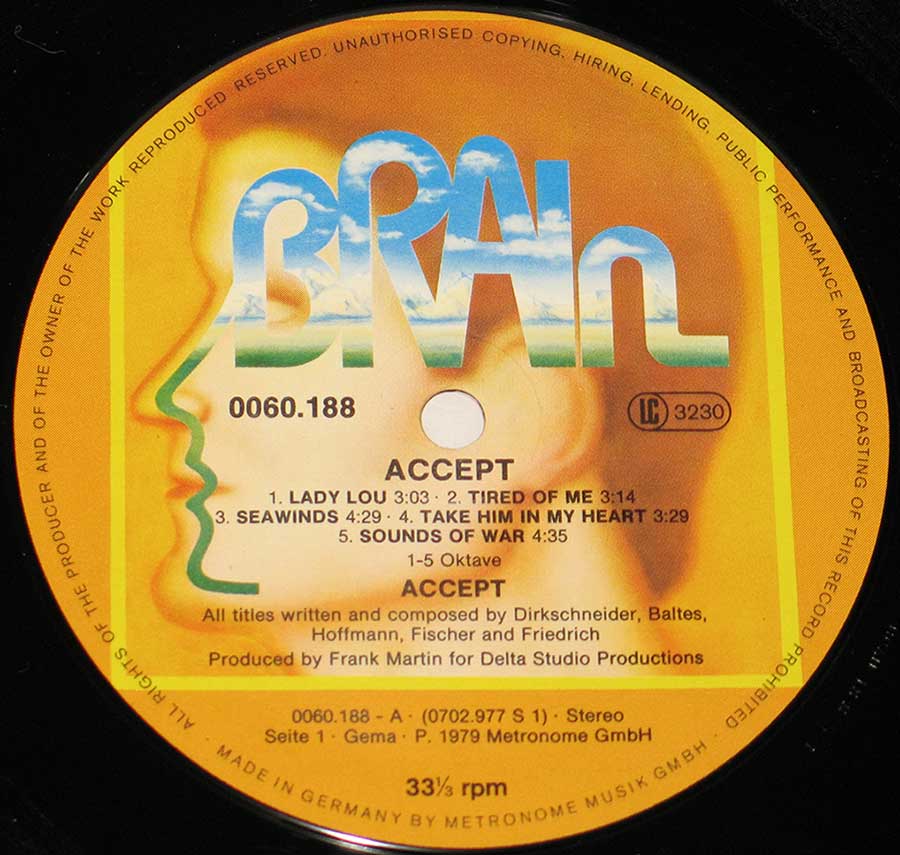 Close-up of the record label for the German heavy metal band Accept. The label says that the record is a 12-inch vinyl LP and that it was made in Germany by Metronome Musik GmbH. One of the tracks is called "Lady Lou" and it was released in 1979. Some of other songs on the album are "Tired Of Me," "Seawinds," "Take Him In My Heart," and "Sounds Of War." The record label also says that the songs were written and composed by Accept members Udo Dirkschneider, Peter Baltes, Wolf Hoffmann, Jörg Fischer, and Frank Friedrich. The record was produced by Frank Martin for Delta Studio Productions.