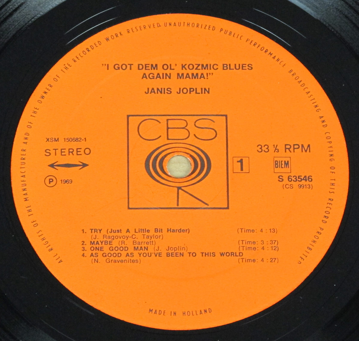 Close-up of CBS record label for Janis Joplin’s 'I Got Dem Ol’ Kozmic Blues Again Mama!' Side 1, featuring a bright orange background, bold black text, tracklist, and the iconic CBS 'walking eye' logo surrounding the spindle hole. Pressed in Holland, 1969.