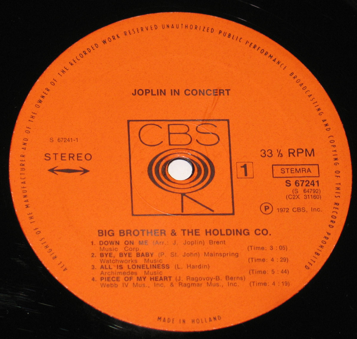 Close-up of CBS Orange label for 'Joplin In Concert' Side One. The label features bold black text on an orange background, with the CBS logo centered above the spindle hole. Tracklist includes 'Down On Me,' 'Bye, Bye Baby,' 'All Is Loneliness,' and 'Piece of My Heart.' Pressed in Holland, 1972, catalog number S 67241.