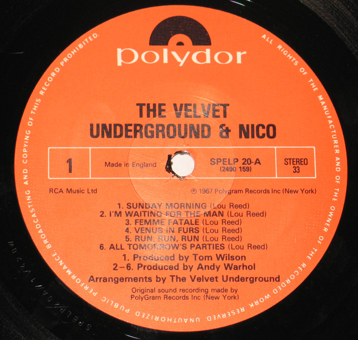 Close-up of Side One label of The Velvet Underground & Nico UK LP, red Polydor label design with tracklist including 'Sunday Morning' and 'Femme Fatale', catalog number SPELP 20-A, Stereo 33 format, produced by Andy Warhol and Tom Wilson, arranged by The Velvet Underground. Made in England by RCA Music Ltd and © 1967 Polygram Records Inc.