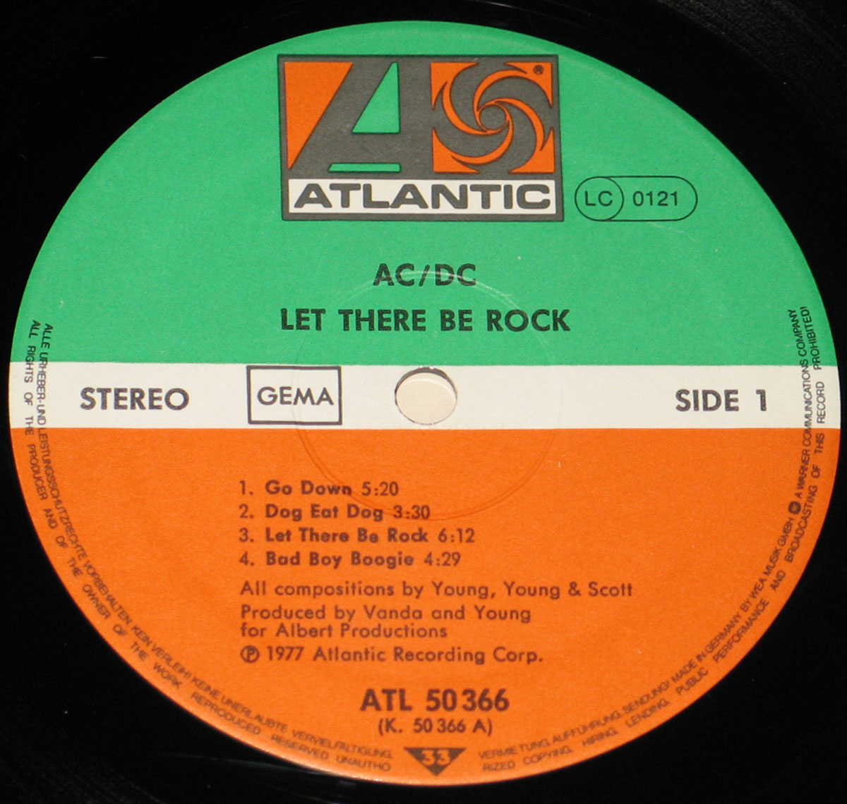 Close-up of the Side One record label for AC/DC’s 'Let There Be Rock' (German Release) on Atlantic Records. The label features a bold two-tone design: green upper half and orange lower half, divided by a white horizontal stripe containing the 'Stereo' marking, the GEMA rights society box, and side designation. The Atlantic Records logo appears prominently at the top in orange and grey. Below, the album title and band name are printed in black, followed by the track listing for Side One with durations. Production credits note Vanda and Young for Albert Productions, and 1977 Atlantic Recording Corp., along with the catalog number ATL 50366.