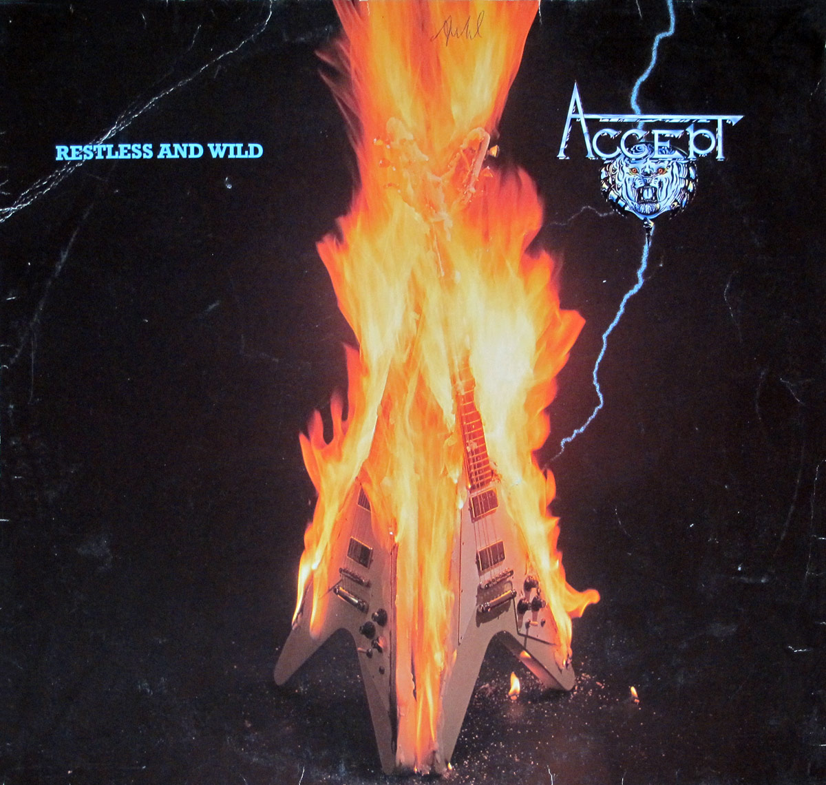 Two burning Gibson Flying V's burning into flames of the album front cover of "Restless and Wild" by Accept.  
