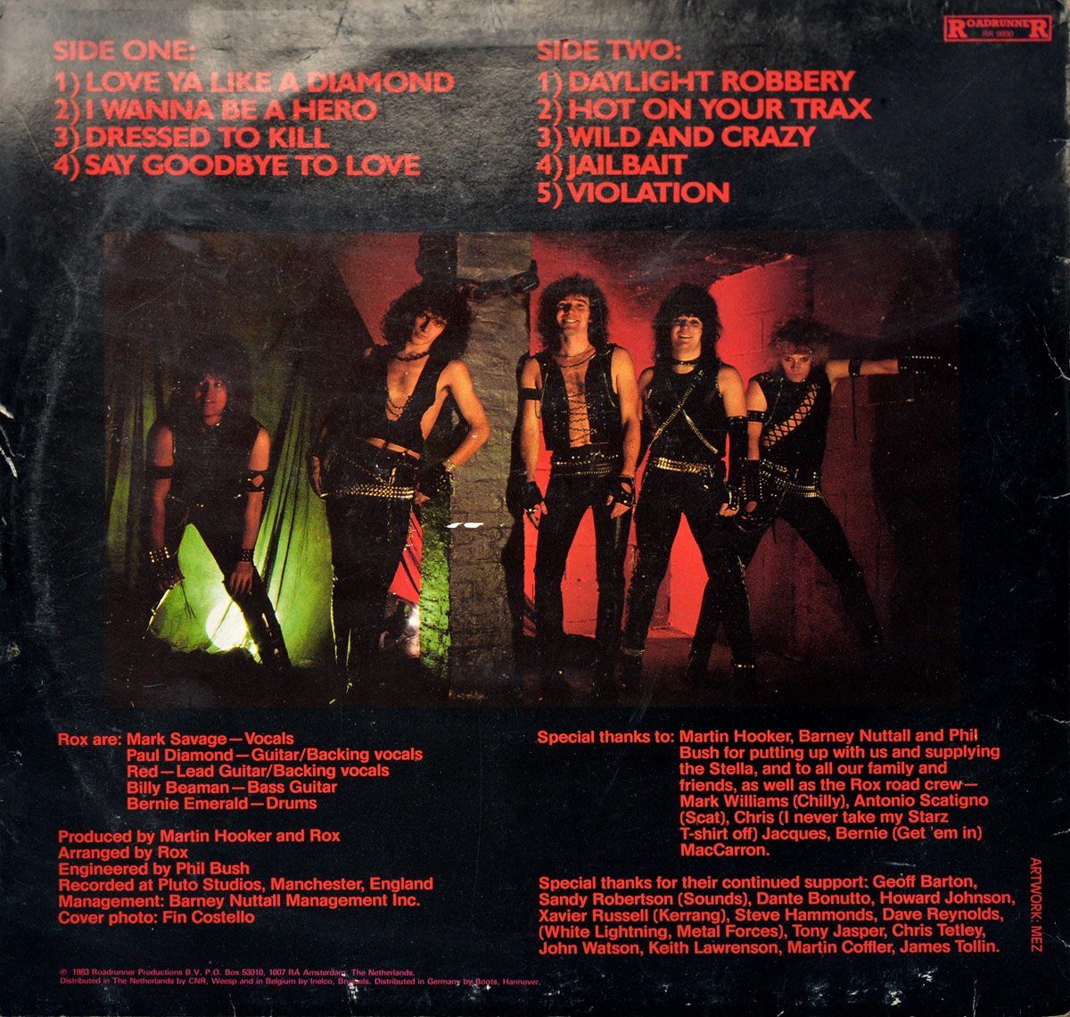 Back cover of Rox’s Violent Breed album featuring a central image of the band members in leather and metal-studded outfits, standing against a gritty background with green and red lighting. Production credits and acknowledgments are listed in red text around the image, along with the Roadrunner Records logo in the top right corner.