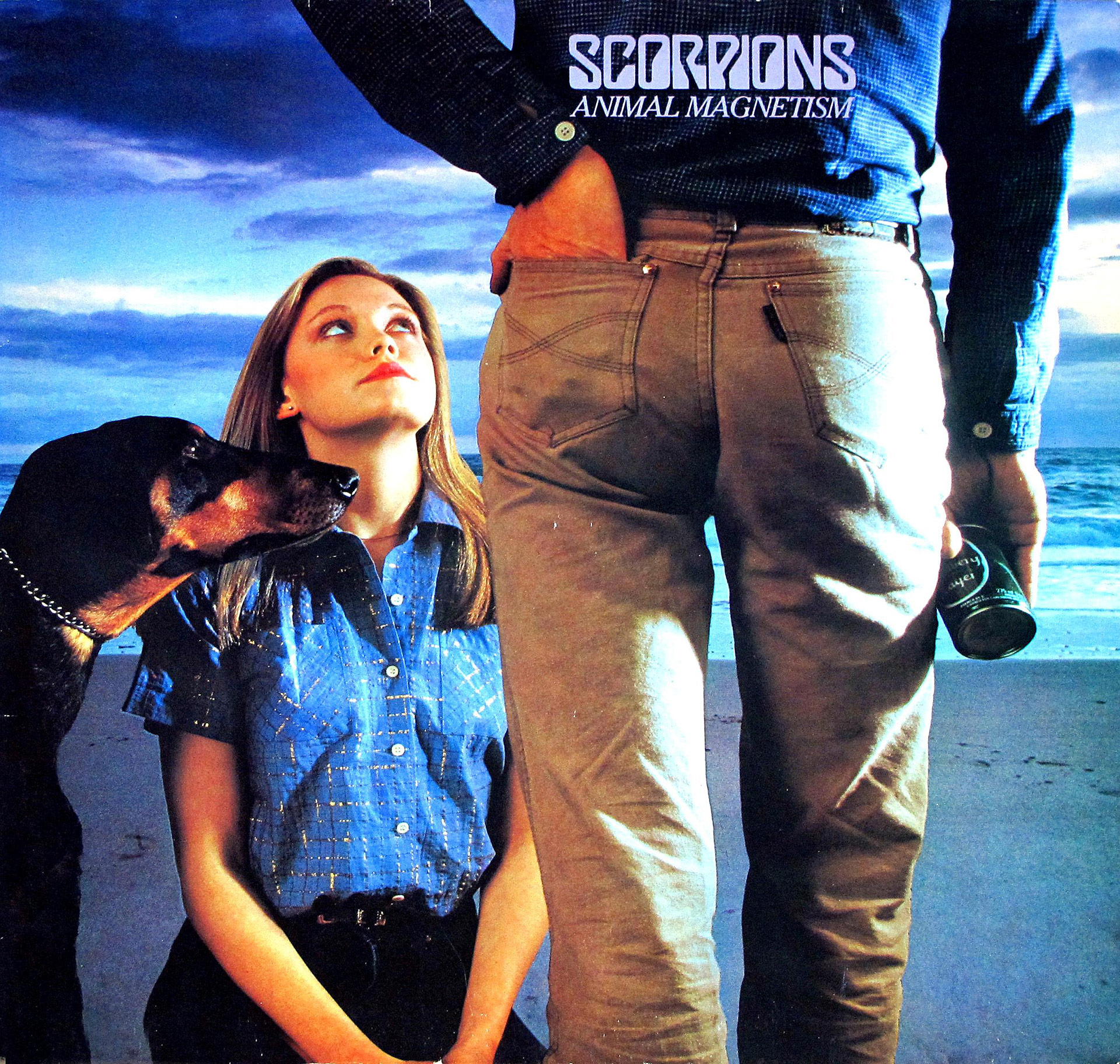 Album cover of Scorpions’ Animal Magnetism (1980). Features a beach scene with a woman seated on the sand looking up at a standing man holding a beer can, with a Doberman dog also gazing upward. The band’s name and album title are displayed at the top in bold, metallic-styled text