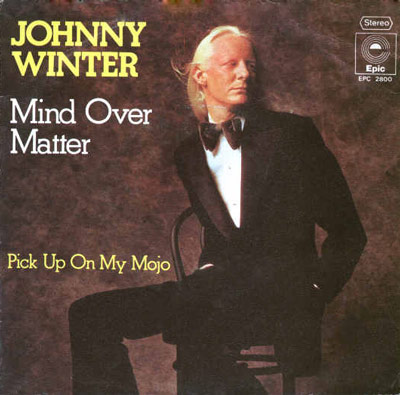 Album cover for Johnny Winter's 'Mind Over Matter' single, featuring Winter in a tuxedo with song titles in yellow and white text on a warm brown background, and Epic Records branding