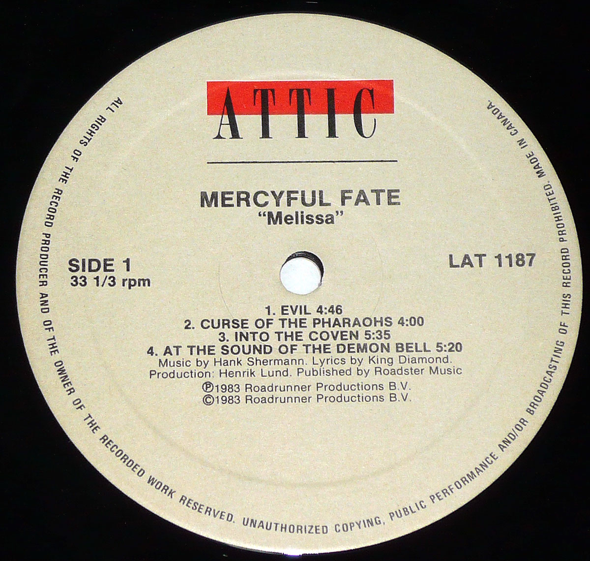 Close-up of the Canadian vinyl record label for Mercyful Fate’s 1983 album “Melissa,” released by Attic Records. The label has a cream-colored background with black text, featuring the red and black “Attic” logo at the top. “Mercyful Fate” and “Melissa” are printed in bold black letters, with the tracklist for Side 1 displayed below, including song titles, durations, and credits. The outer edge contains a copyright warning and “Made in Canada” text, indicating this is a Canadian pressing of the album.