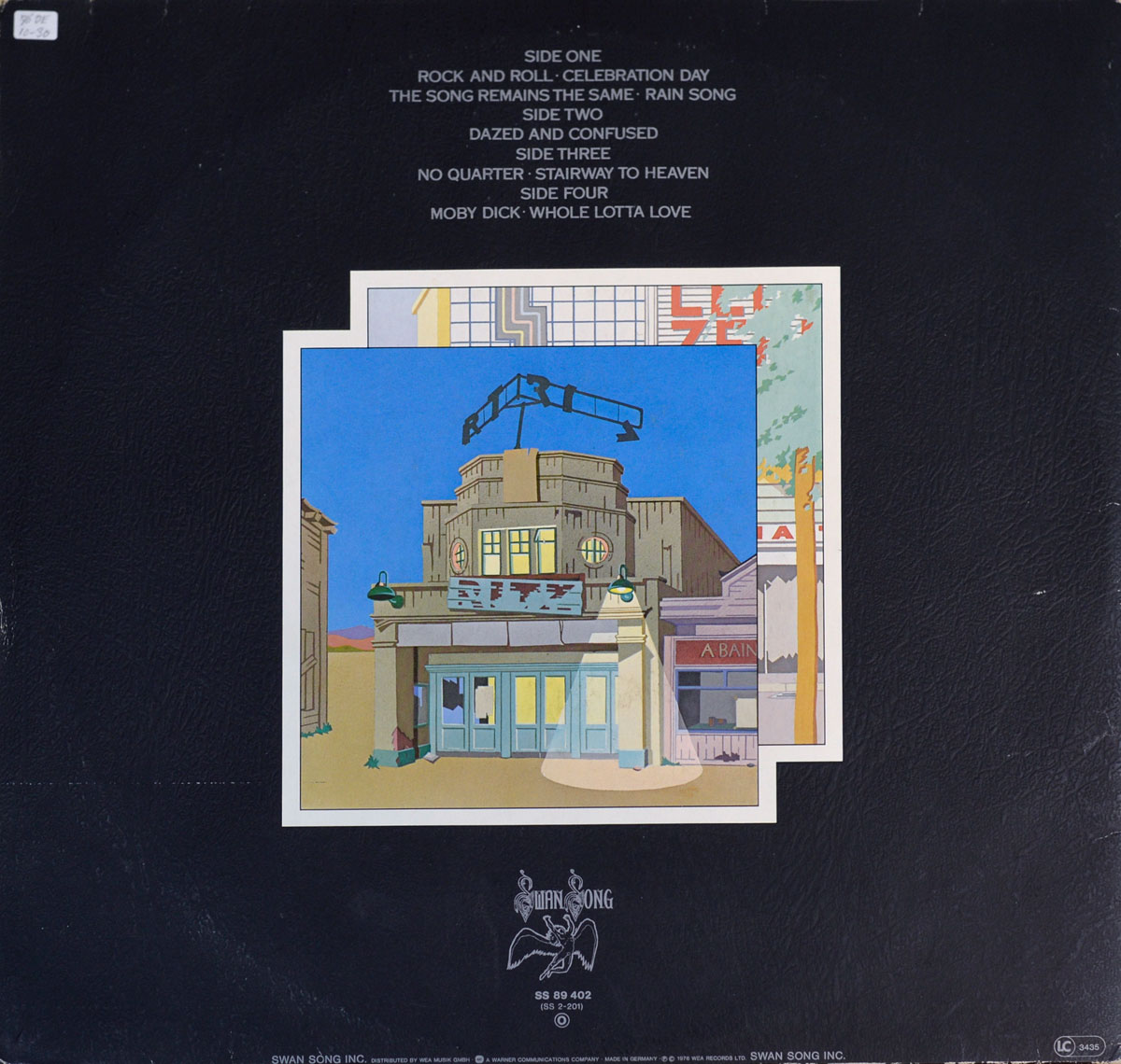 Album back cover on a matte black, leatherette-textured field. At the top center, small silver text lists the four sides and tracks: Side One (Rock and Roll, Celebration Day, The Song Remains the Same, Rain Song), Side Two (Dazed and Confused), Side Three (No Quarter, Stairway to Heaven), Side Four (Moby Dick, Whole Lotta Love). Below, a crisp white-bordered illustration shows an art-deco cinema façade under a blue sky, with round windows, glass doors glowing yellow, and a broken rooftop sign arm. Near the bottom center, the Swan Song winged figure logo appears in silver with small catalog text “SS 89 402”; at lower right is a tiny LC 3445 mark. A small white price sticker sits in the upper-left corner; minor shelf scuffs appear along edges.