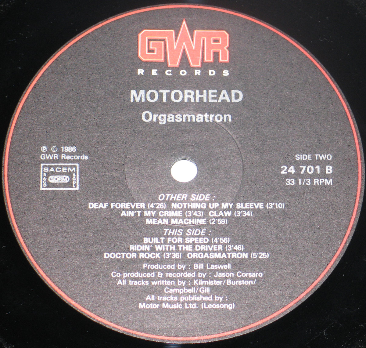 Close-up of the Side Two record label from Motörhead "Orgasmatron", showing a dark grey GWR Records label on black vinyl. The red GWR logo is at the top, with Motörhead and Orgasmatron printed beneath. Side Two, catalogue number 24 701 B, 33 1/3 RPM, SACEM/SDRM box, track credits, and production details are visible.
