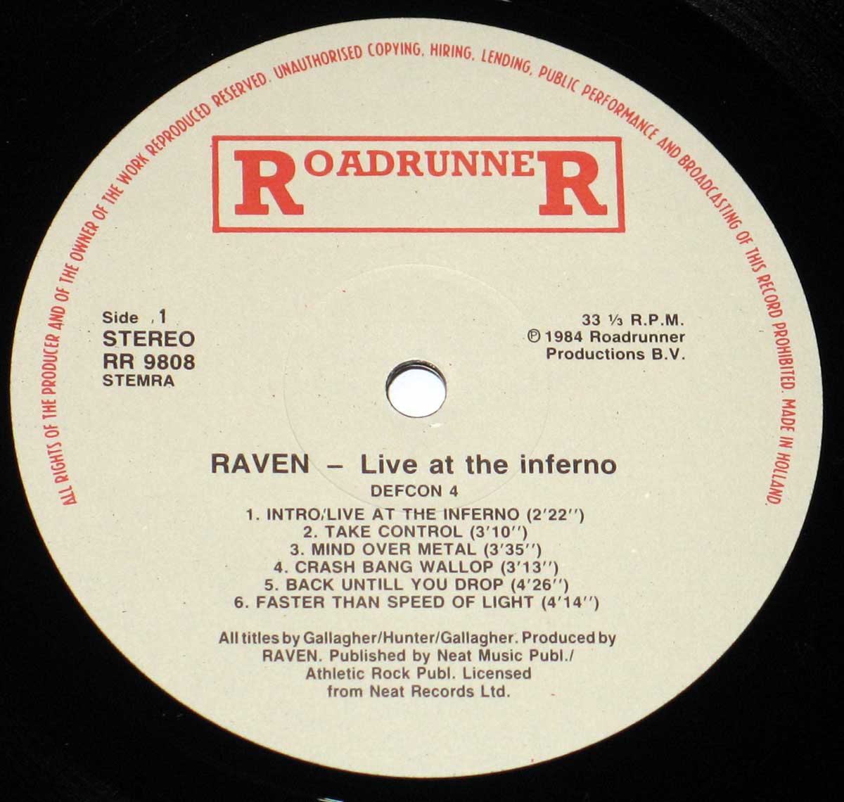 Close-up of the RoadrunneR record label for Raven Live at the Inferno, photographed from the vinyl record itself. The circular paper label sits around the spindle hole at the centre of the disc, with printed text arranged in rings and blocks, showing the band name, album title, record company branding, catalogue details, and other production information.