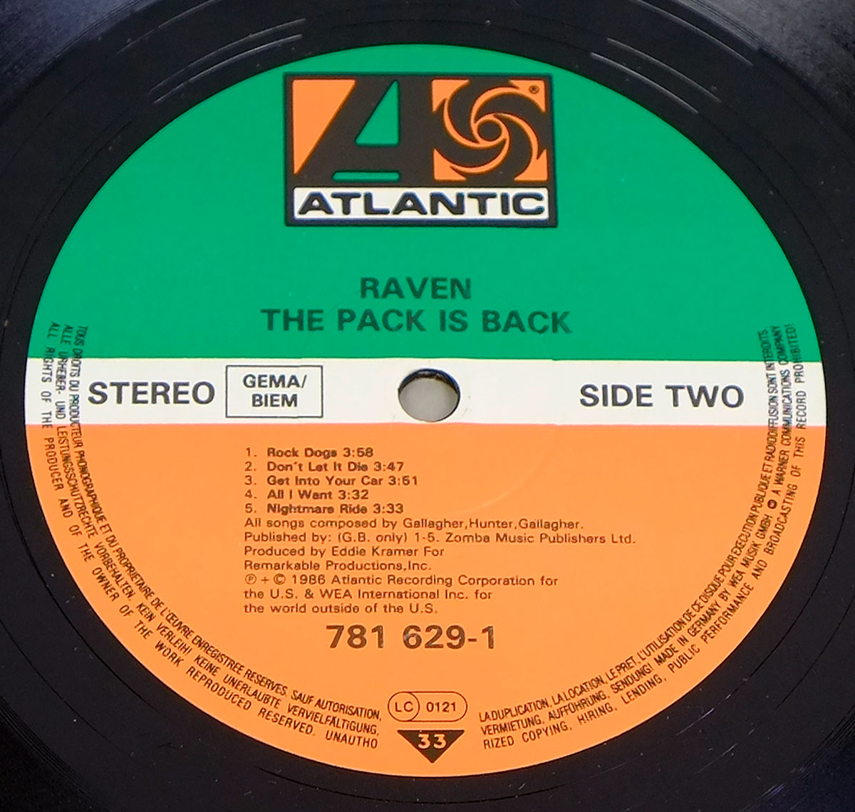 Close-up of Side Two label for Raven The Pack Is Back on Atlantic Records. The label has a green upper half, white centre band and orange lower half, with the Atlantic logo at the top. It shows RAVEN, THE PACK IS BACK, STEREO, GEMA/BIEM, SIDE TWO, five track titles with timings, catalogue number 781 629-1, LC 0121, 33 speed mark and multilingual rim text.