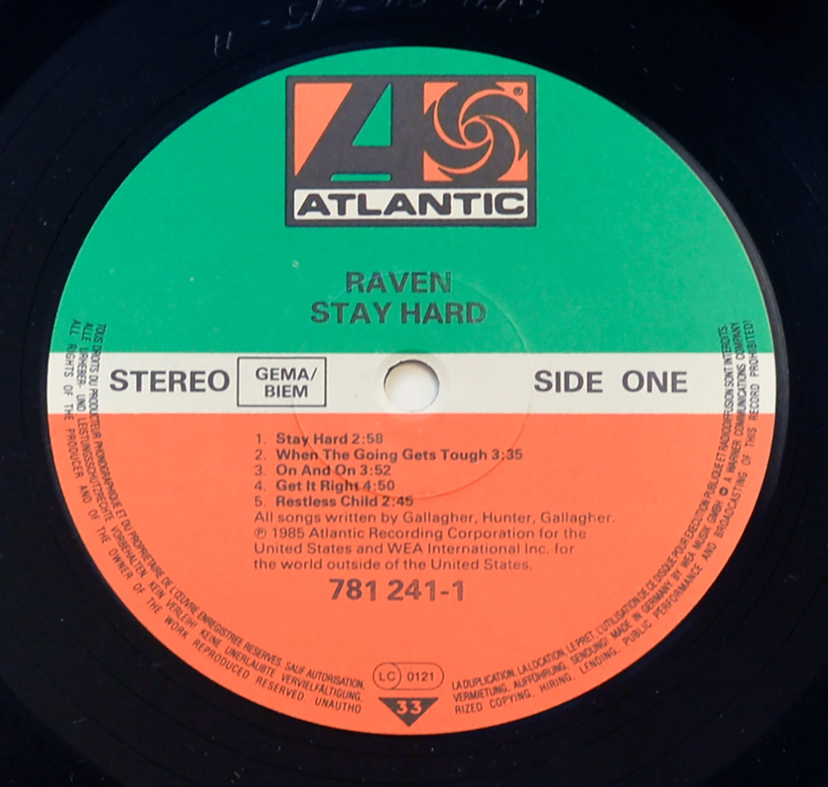 Close-up of Raven Stay Hard Side One vinyl record label on Atlantic Records, with the green, white, and orange label design, Atlantic logo at top, Raven and Stay Hard printed above the spindle hole, stereo and GEMA/BIEM at left, Side One at right, track titles and durations below, catalogue number 781 241-1, LC 0121, and 33 speed triangle near the bottom.