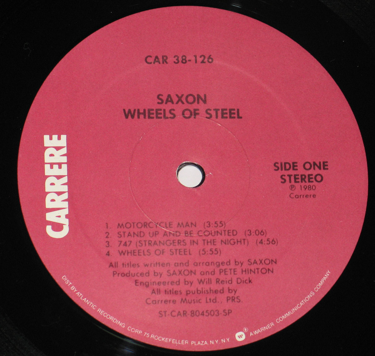 Red record label of Saxon’s Wheels of Steel album by Carrere Records, featuring the band name, album title, catalog number, and production credits with a vertical Carrere logo on the left.