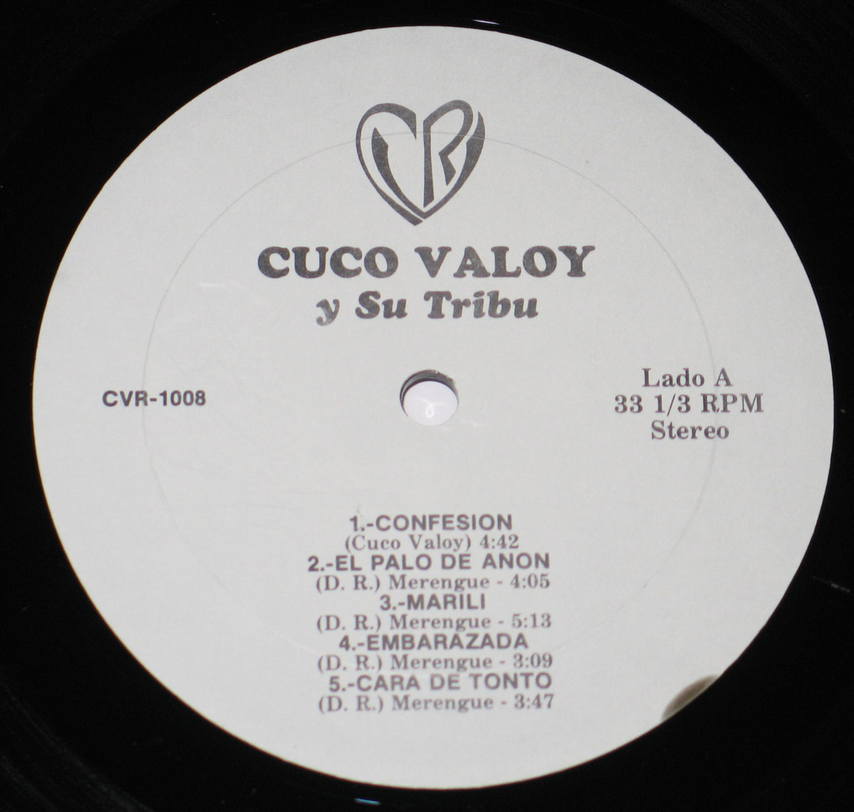 Close-up of the vinyl record label for 'Cuco Valoy y Su Tribu'. The label is light grey with black text, featuring the CVR logo at the top, a stylized heart with the letters 'CVR' inside. The album title is in bold uppercase letters, and the tracklist for Lado A is neatly arranged below, indicating song durations and genres.