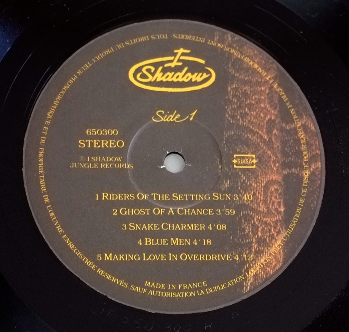 Close-up of Side One vinyl label for I SHADOW – An I For An I. The label features golden text over a brown and rust-red paisley design with tracklist, catalog number 650300, and the SUISA logo.