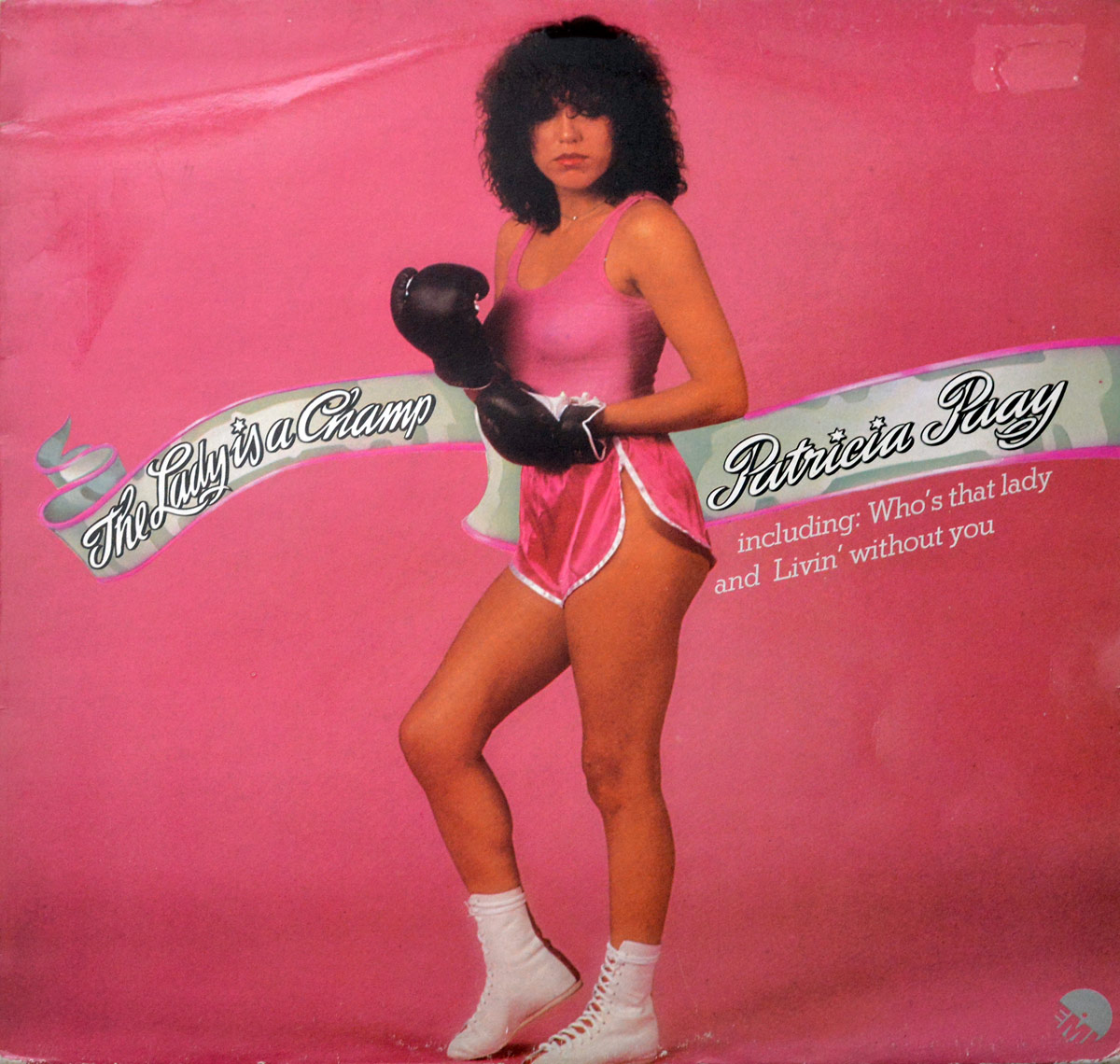 Patricia Paay on the album cover of The Lady Is A Champ stands in front of a bold pink background, dressed in satin pink boxing attire with black gloves, white laced boots, and a confident gaze. The album title and her name are displayed in vintage script across a ribbon graphic. Featured songs are highlighted on the right
