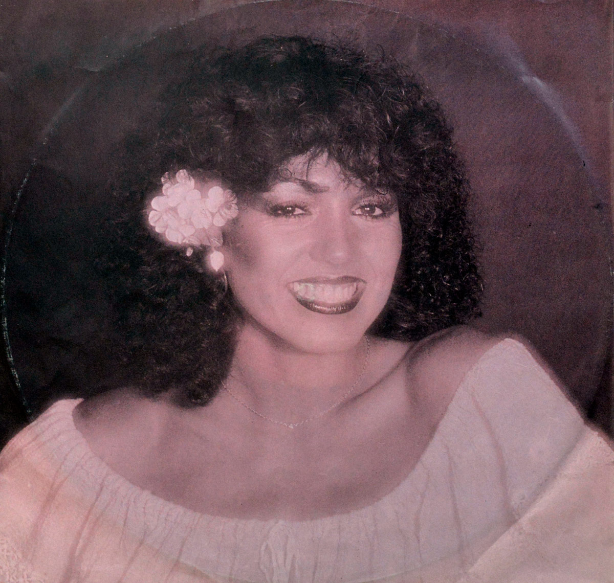 Smiling Patricia Paay portrait with soft curls, flower tucked behind her ear, and off-shoulder blouse. The lighting is warm and intimate, printed on the inner sleeve of the vinyl.