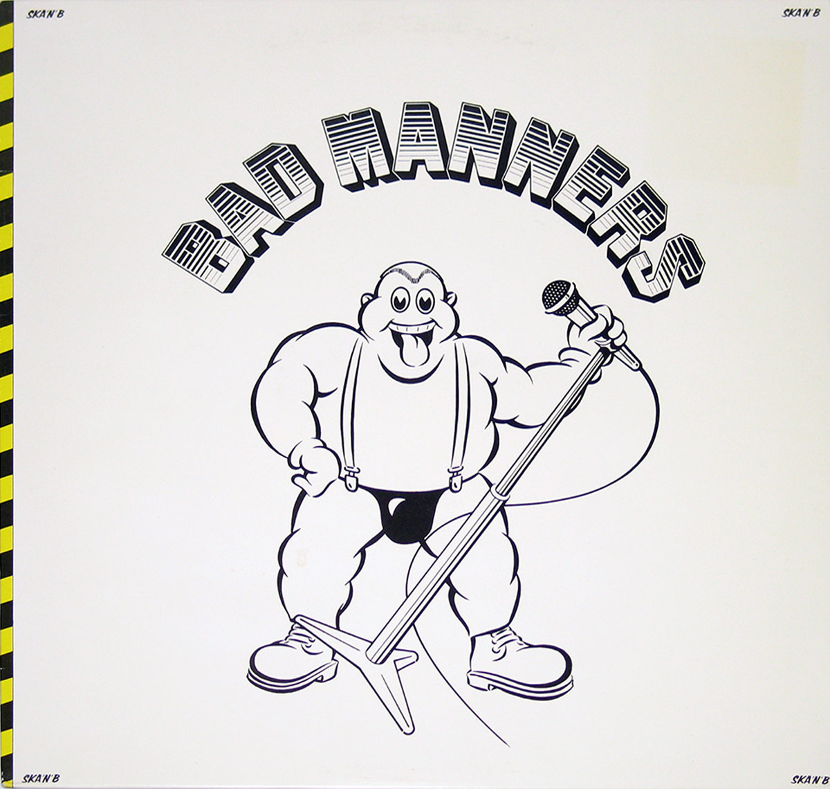 Front cover of Bad Manners' 1980 album 'Ska 'n' B' featuring a bold black-and-white cartoon illustration of a bald, muscular man with a wide grin and tongue out, holding a microphone on a stand. He wears suspenders, black briefs, and boots. The band's name 'BAD MANNERS' arches in stylized block letters above him. The border on the left features a vertical yellow-and-black hazard stripe pattern. The corners of the cover display the title 'SKA'N'B' in small black type