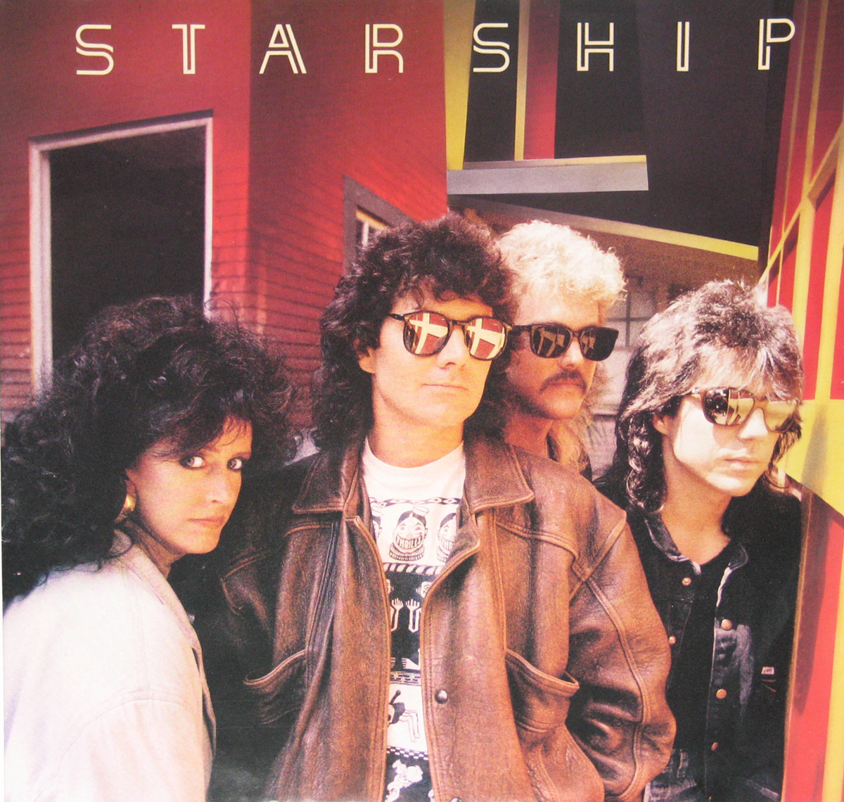 Photo from the inner sleeve of Starship's 1987 album 'No Protection' showing the four band members wearing sunglasses, standing close together in front of a bold, modern building façade.