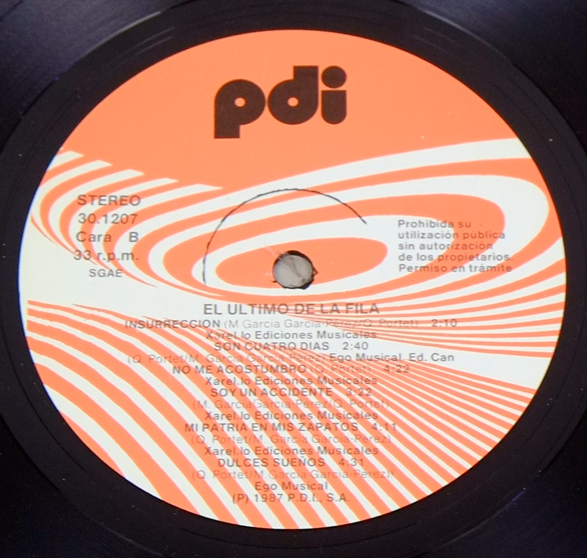 Side B of Último de la Fila’s 'Nuevas Mezclas' vinyl record. The label has an abstract orange and white swirl pattern, black text with track names, durations, and production details. The PDI logo is at the top, with 'STEREO' and '33 r.p.m.' below. A hole in the center is visible, surrounded by glossy black vinyl. A Spanish notice warns against unauthorized use.