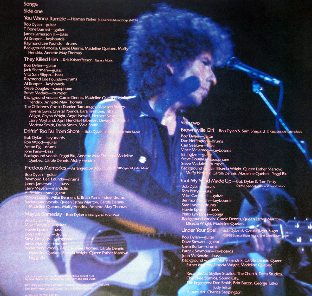 Back cover of Bob Dylan’s Knocked Out Loaded LP featuring a live photo of Dylan at a microphone with text overlays listing song titles, musician credits, and production details.