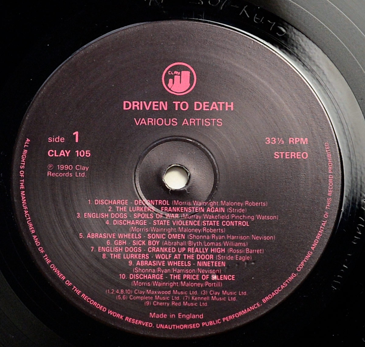 Side 1 record label of VA - Driven to Death punk compilation LP. Features tracklist with band names and songwriters in red on black vinyl. UK Clay Records CLAY 105.